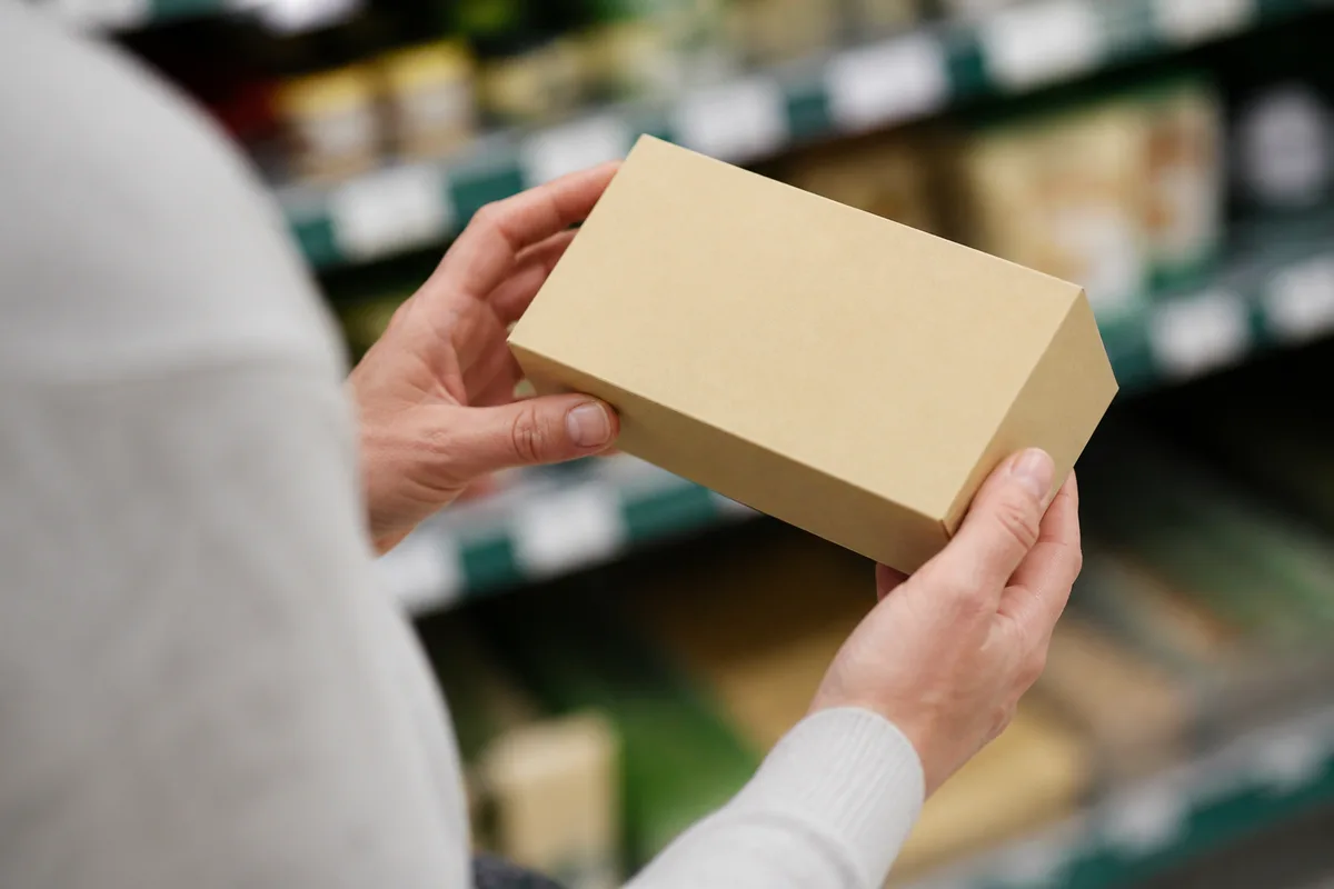 Dos d&rsquo;un paquet alimentaire tenu à la main dans un rayon de supermarché